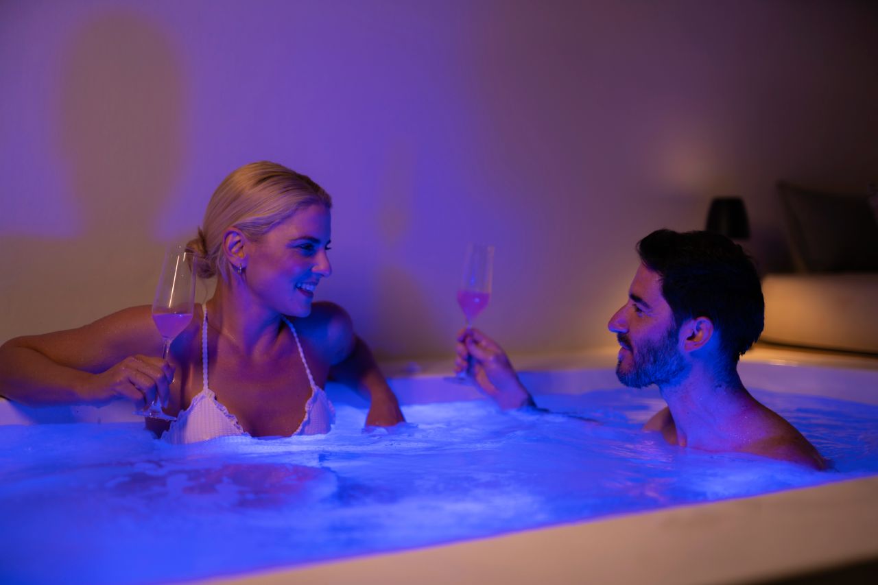 Oia Mansion - Luxurious Mansion Rental in Santorini - Couple relaxing in Jacuzzi